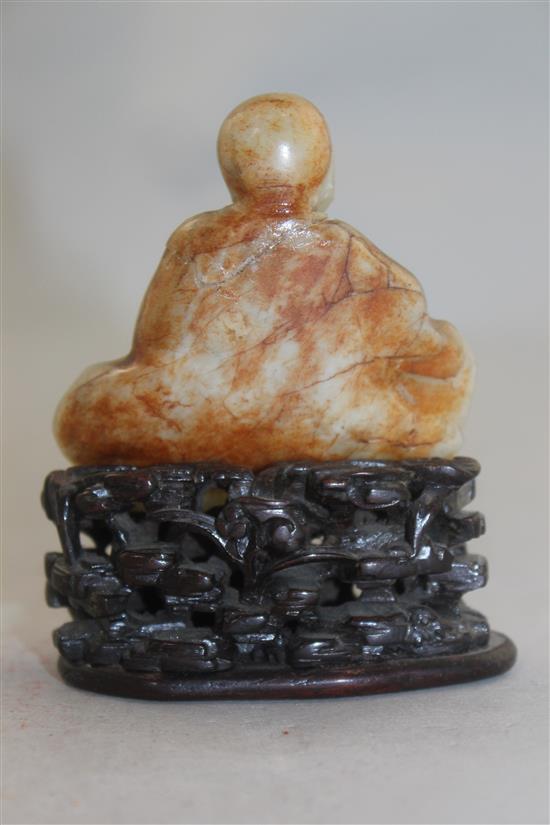A Chinese white and russet jade carving of a luohan, 18th / 19th century, 6.7cm, neck broken and restuck, intricately carved rosewood s